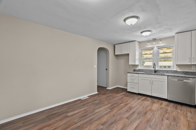 7832 Main St, Walsh, IL 62297 - kitchen featuring stainless steel dishwasher, arched walkways, dark wood-style flooring, white cabinets, and a sink