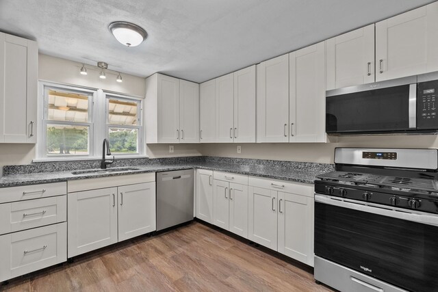 7832 Main St, Walsh, IL 62297 - kitchen featuring appliances with stainless steel finishes, a sink, white cabinetry, wood finished floors, and dark stone countertops