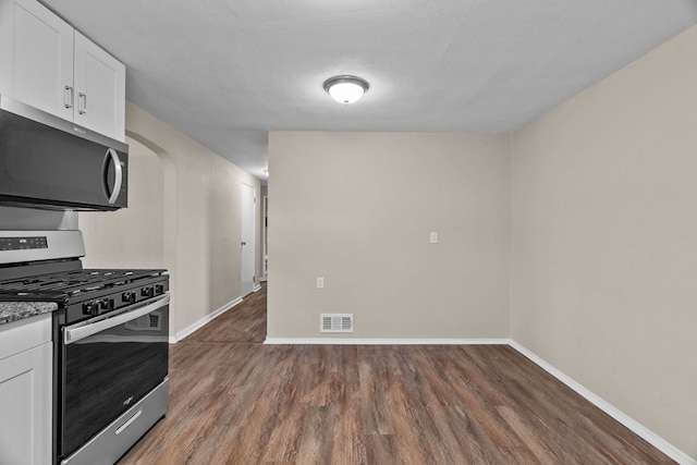 7832 Main St, Walsh, IL 62297 - kitchen with appliances with stainless steel finishes, wood finished floors, baseboards, white cabinets, and arched walkways