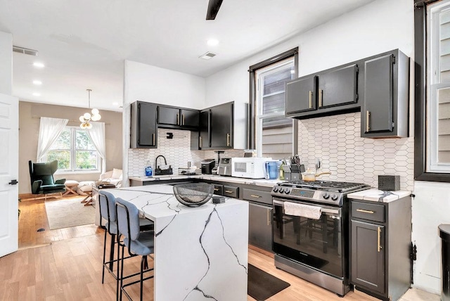 4926 S Winchester Ave, Chicago, IL 60609 - kitchen with stainless steel gas range oven, a kitchen bar, light wood-style flooring, light stone counters, and recessed lighting