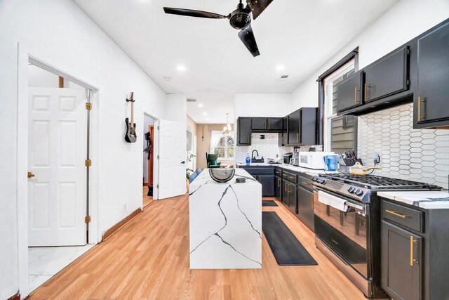 4926 S Winchester Ave, Chicago, IL 60609 - kitchen featuring stainless steel gas range, a kitchen island, a ceiling fan, backsplash, and white microwave