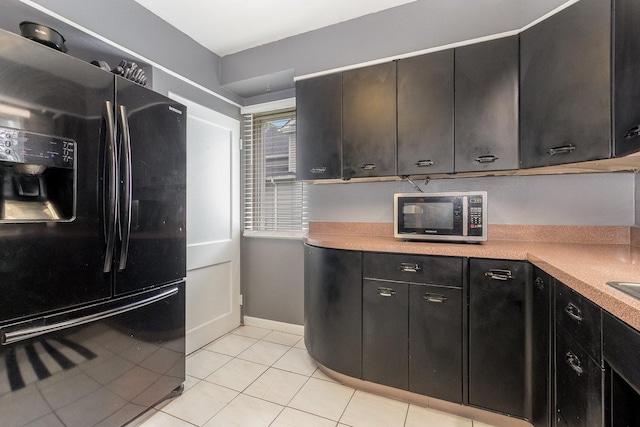 614 Oak Ave, Aurora, IL 60506 - kitchen featuring black refrigerator with ice dispenser, stainless steel microwave, light countertops, light tile patterned floors, and dark cabinetry