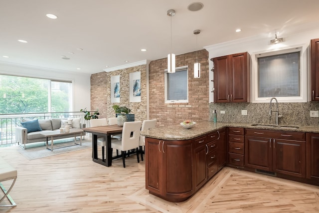 2433 W Haddon Ave Unit 1E, Chicago, IL 60622 - kitchen featuring a sink, crown molding, a peninsula, light stone countertops, and hanging light fixtures