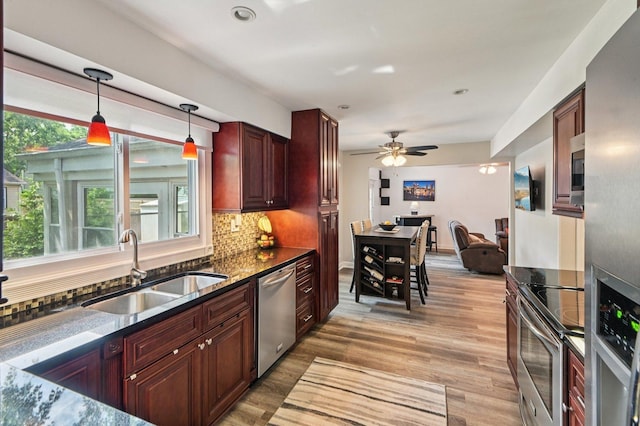2313 Modaff Rd, Naperville, IL 60565 - kitchen featuring appliances with stainless steel finishes, a sink, light wood-type flooring, decorative backsplash, and hanging light fixtures