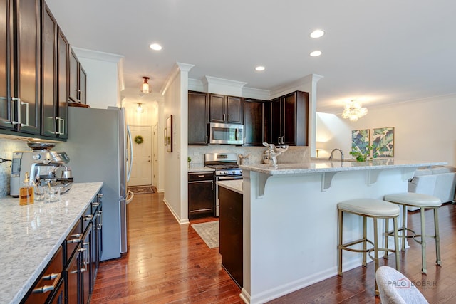 769 N Winchester Dr, Palatine, IL 60067 - kitchen with appliances with stainless steel finishes, a breakfast bar, dark wood-type flooring, decorative backsplash, and dark brown cabinets
