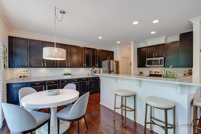 769 N Winchester Dr, Palatine, IL 60067 - kitchen featuring appliances with stainless steel finishes, decorative backsplash, crown molding, dark brown cabinets, and a kitchen bar