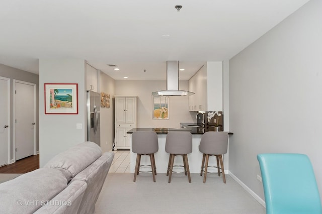 362 Kelburn Rd Unit 124, Deerfield, IL 60015 - kitchen featuring wall chimney range hood, stainless steel fridge, a kitchen bar, white cabinetry, and a peninsula