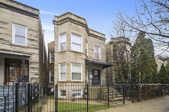 648 N Drake Ave, Chicago, IL 60624 - townhome / multi-family property featuring stone siding, a fenced front yard, and a gate