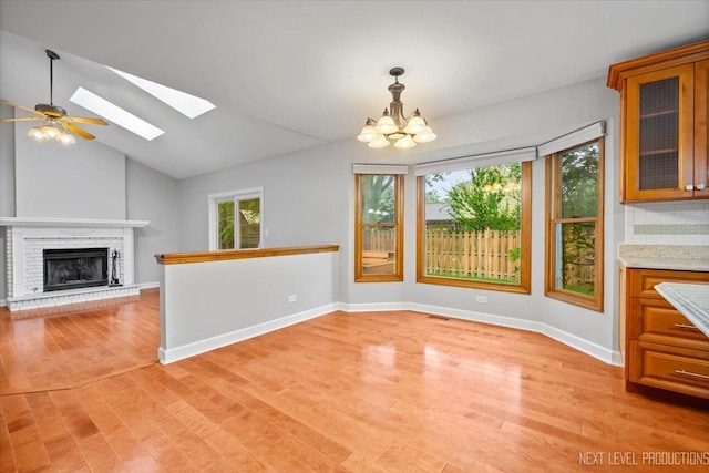 2556 Leach Dr, Naperville, IL 60564 - unfurnished dining area with a chandelier, light wood-style floors, a skylight, baseboards, and a fireplace