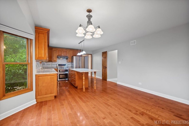2556 Leach Dr, Naperville, IL 60564 - kitchen with appliances with stainless steel finishes, under cabinet range hood, a chandelier, a sink, and light countertops
