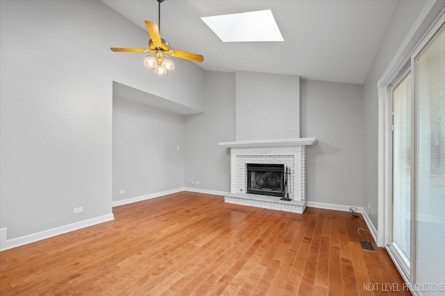 2556 Leach Dr, Naperville, IL 60564 - unfurnished living room featuring a fireplace, plenty of natural light, a skylight, wood finished floors, and high vaulted ceiling