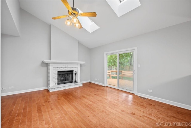 2556 Leach Dr, Naperville, IL 60564 - unfurnished living room with a skylight, wood finished floors, a brick fireplace, baseboards, and high vaulted ceiling