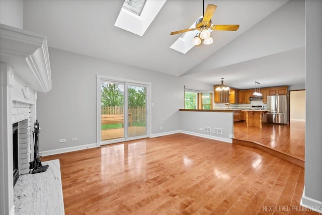 2556 Leach Dr, Naperville, IL 60564 - unfurnished living room featuring a skylight, light wood-type flooring, a fireplace, baseboards, and high vaulted ceiling