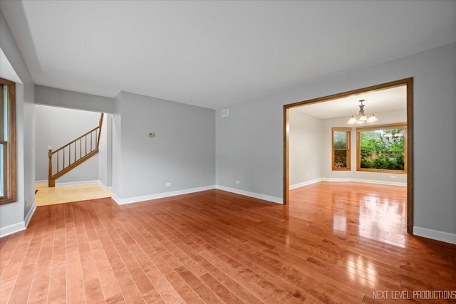 2556 Leach Dr, Naperville, IL 60564 - spare room featuring a chandelier, stairs, light wood-style floors, and baseboards