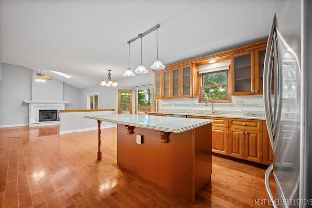 2556 Leach Dr, Naperville, IL 60564 - kitchen with freestanding refrigerator, a sink, brown cabinetry, a brick fireplace, and a chandelier