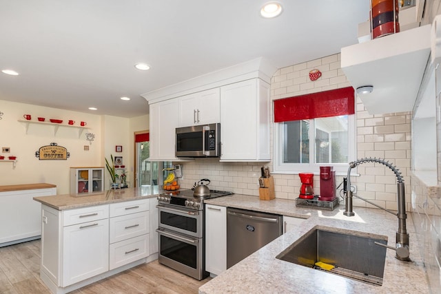 2715 Lahinch Dr, Aurora, IL 60503 - kitchen featuring appliances with stainless steel finishes, a peninsula, white cabinetry, decorative backsplash, and recessed lighting