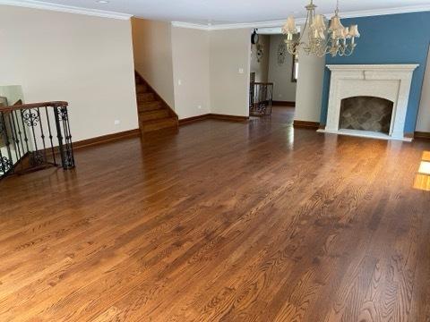 473 S Edgewood Ave, Wood Dale, IL 60191 - unfurnished living room featuring a chandelier, ornamental molding, baseboards, wood finished floors, and a fireplace with flush hearth