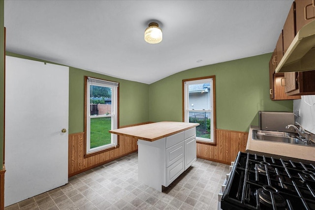 913 N Mason St, Bloomington, IL 61701 - kitchen featuring wall chimney exhaust hood, a wainscoted wall, lofted ceiling, range with gas stovetop, and wood walls