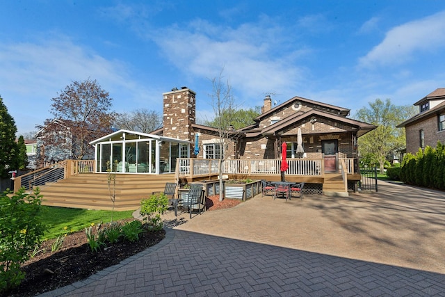 1424 Glencoe Ave, Highland Park, IL 60035 - rear view of property featuring a sunroom, a chimney, brick siding, and a patio