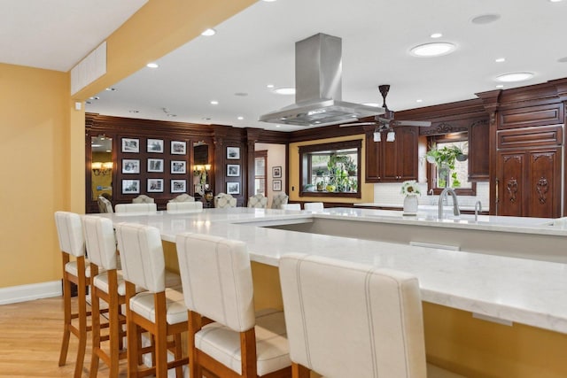 1424 Glencoe Ave, Highland Park, IL 60035 - kitchen with island exhaust hood, ceiling fan, recessed lighting, light stone counters, and a breakfast bar