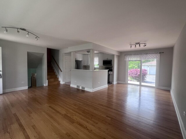 7011 Avon Ave, Oak Lawn, IL 60453 - unfurnished living room with rail lighting, wood finished floors, stairway, and baseboards