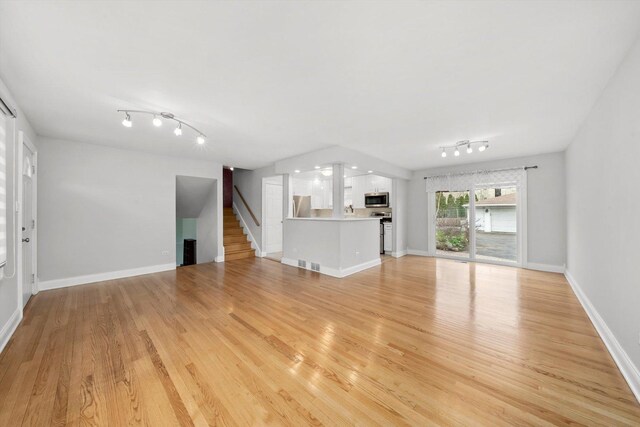 7011 Avon Ave, Oak Lawn, IL 60453 - unfurnished living room with rail lighting, stairs, light wood finished floors, and baseboards