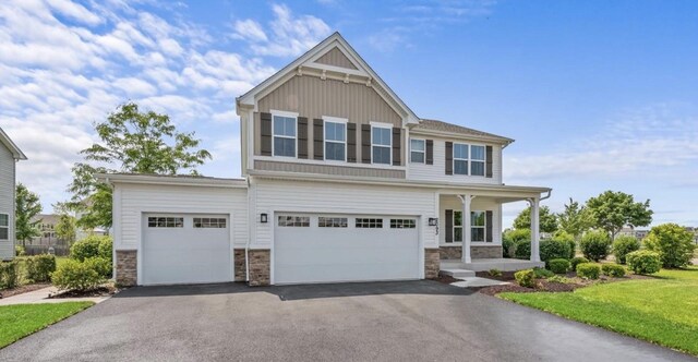 2093 Squire Cir, Yorkville, IL 60560 - view of front facade with asphalt driveway, stone siding, covered porch, board and batten siding, and an attached garage