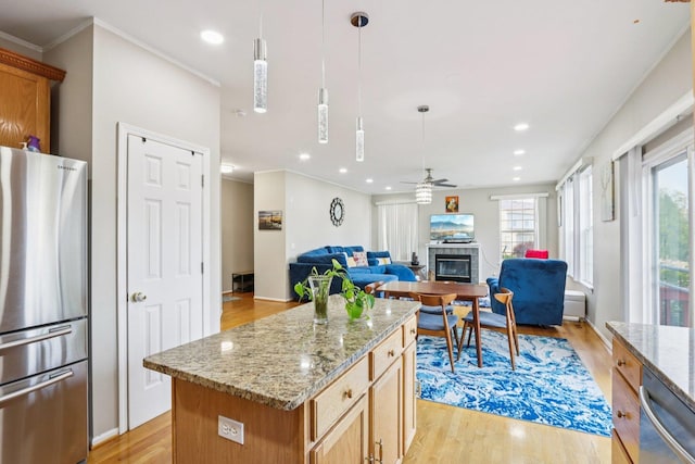 263 Thrush Cir, Lindenhurst, IL 60046 - kitchen featuring stainless steel appliances, a glass covered fireplace, light wood-type flooring, ceiling fan, and light stone counters