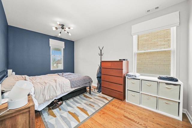 3238 N Whipple St, Chicago, IL 60618 - bedroom with light wood-type flooring, a chandelier, and baseboards