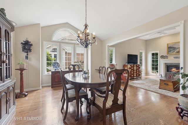 13922 Steepleview Ln, Lemont, IL 60439 - dining area featuring light wood-style floors, a chandelier, healthy amount of natural light, vaulted ceiling, and a glass covered fireplace