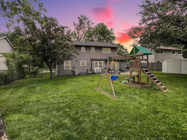 4400 Waubansie Ln, Lisle, IL 60532 - back of house at dusk featuring a playground, a fenced backyard, and a storage unit