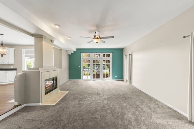 499 Waubonsee Cir, Oswego, IL 60543 - unfurnished living room featuring ceiling fan, carpet flooring, a tiled fireplace, and baseboards