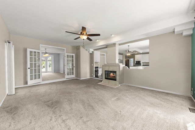 499 Waubonsee Cir, Oswego, IL 60543 - unfurnished living room featuring ceiling fan, carpet floors, baseboards, a tile fireplace, and french doors
