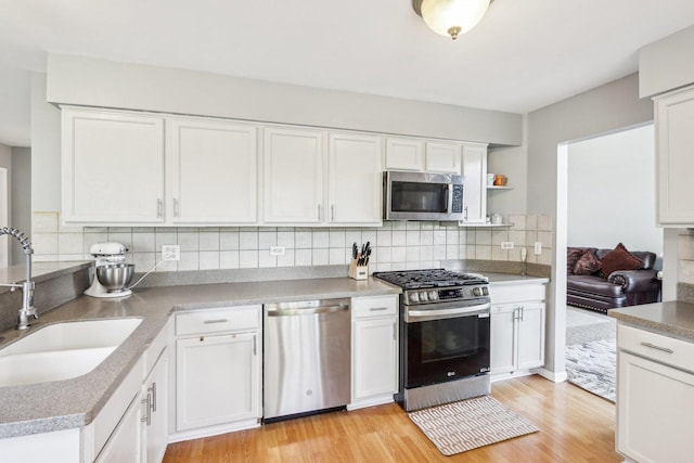 4801 Bordeaux Dr, Lake In The Hills, IL 60156 - kitchen featuring stainless steel appliances, a sink, white cabinets, light wood finished floors, and tasteful backsplash