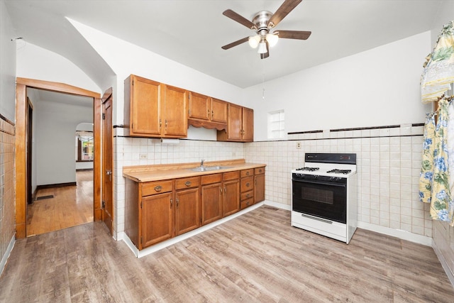 3523 W 60th Pl, Chicago, IL 60629 - kitchen featuring range with gas cooktop, a sink, a ceiling fan, tile walls, and light wood-style flooring