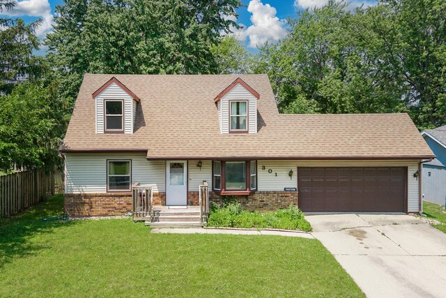 301 Columbia Dr, Normal, IL 61761 - cape cod house featuring a garage, brick siding, concrete driveway, and roof with shingles
