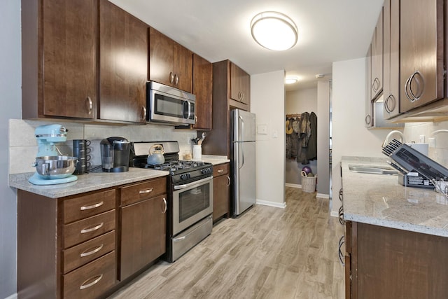 2642 N Windsor Dr Unit 102, Arlington Heights, IL 60004 - kitchen with appliances with stainless steel finishes, light wood-type flooring, tasteful backsplash, dark brown cabinets, and baseboards