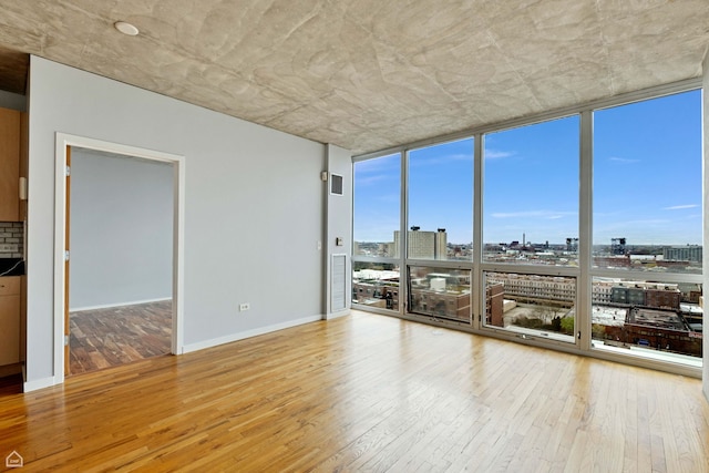 1845 S Michigan Ave Unit 1602, Chicago, IL 60616 - unfurnished room with expansive windows, wood-type flooring, a city view, and baseboards