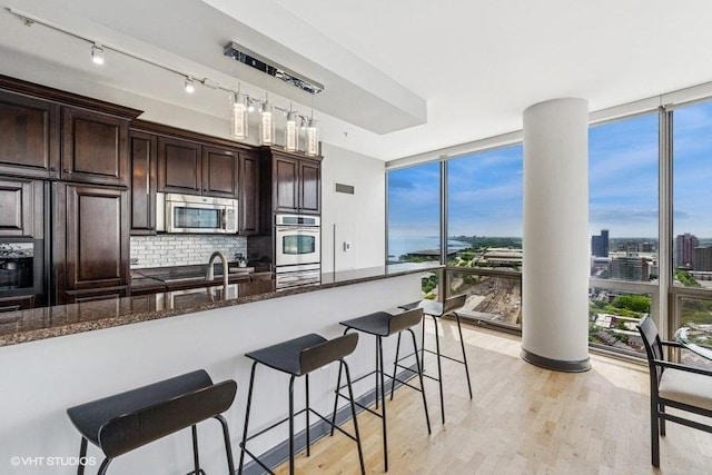 1235 S Prairie Ave Unit 3605, Chicago, IL 60605 - kitchen with appliances with stainless steel finishes, expansive windows, a breakfast bar, backsplash, and dark brown cabinetry