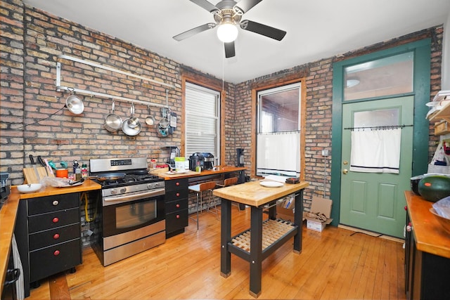 1518 N Kedzie Ave, Chicago, IL 60651 - kitchen with stainless steel gas stove, brick wall, ceiling fan, light wood-type flooring, and wood counters
