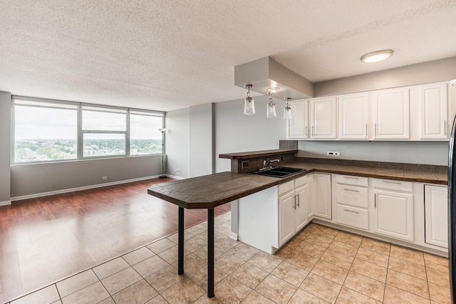 7234 W N Ave Unit 1608, Elmwood Park, IL 60707 - kitchen featuring a sink, a peninsula, white cabinetry, dark countertops, and a textured ceiling