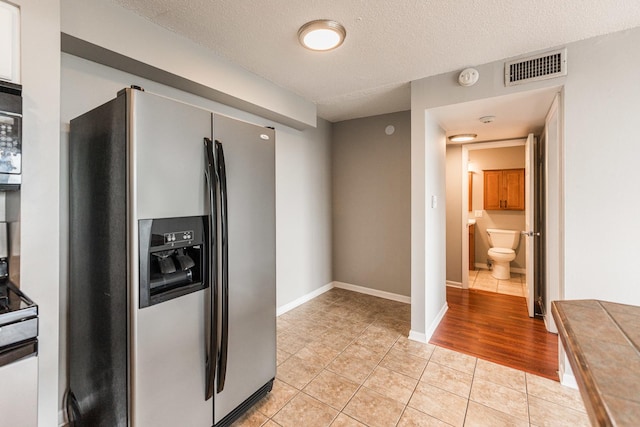 7234 W N Ave Unit 1608, Elmwood Park, IL 60707 - kitchen featuring stainless steel refrigerator with ice dispenser, light tile patterned floors, baseboards, and a textured ceiling