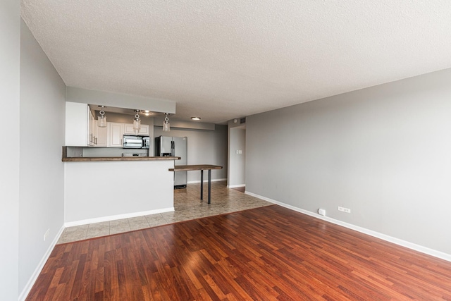 7234 W N Ave Unit 1608, Elmwood Park, IL 60707 - unfurnished living room featuring wood finished floors, baseboards, and a textured ceiling