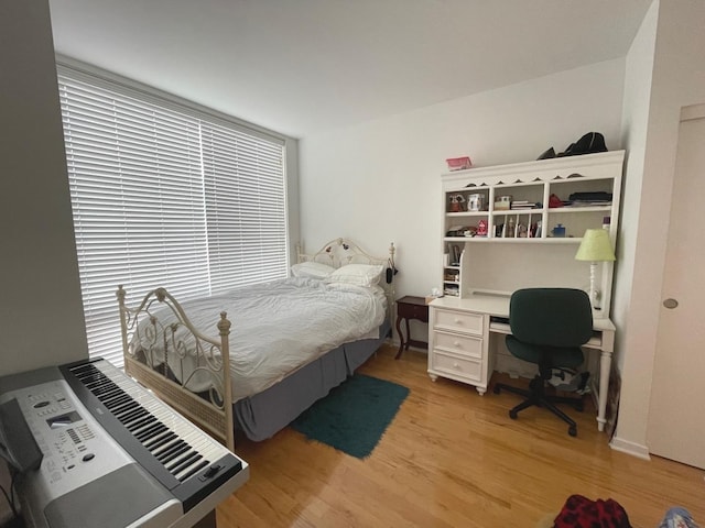 bedroom with light wood-type flooring, an office area, and heating unit