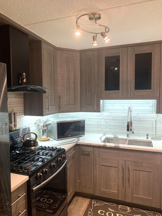 6430 W Belle Plaine Ave Unit 202, Chicago, IL 60634 - kitchen with black range with gas cooktop, wall chimney range hood, a sink, a textured ceiling, and tasteful backsplash