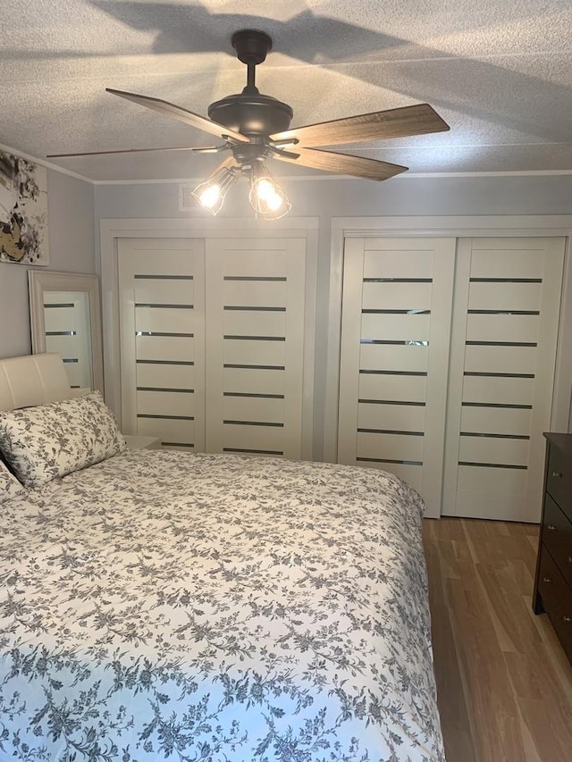 6430 W Belle Plaine Ave Unit 202, Chicago, IL 60634 - bedroom featuring a textured ceiling, dark wood-style floors, a ceiling fan, and two closets