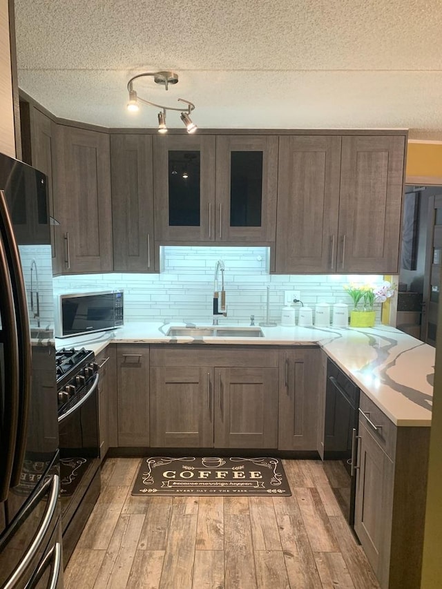 6430 W Belle Plaine Ave Unit 202, Chicago, IL 60634 - kitchen with a sink, black appliances, a textured ceiling, light wood-style floors, and light countertops