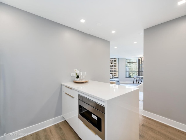 405 N Wabash Ave Unit 2313, Chicago, IL 60611 - kitchen with stainless steel microwave, modern cabinets, a peninsula, light wood-style flooring, and white cabinets