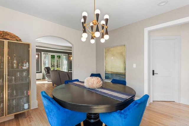 2530 W Morse Ave, Chicago, IL 60645 - dining room featuring arched walkways, wood finished floors, a chandelier, and radiator