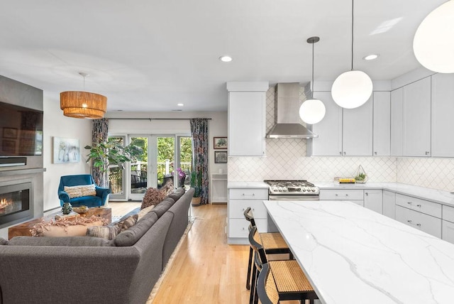 2530 W Morse Ave, Chicago, IL 60645 - kitchen featuring wall chimney range hood, open floor plan, light wood-type flooring, light stone countertops, and decorative backsplash